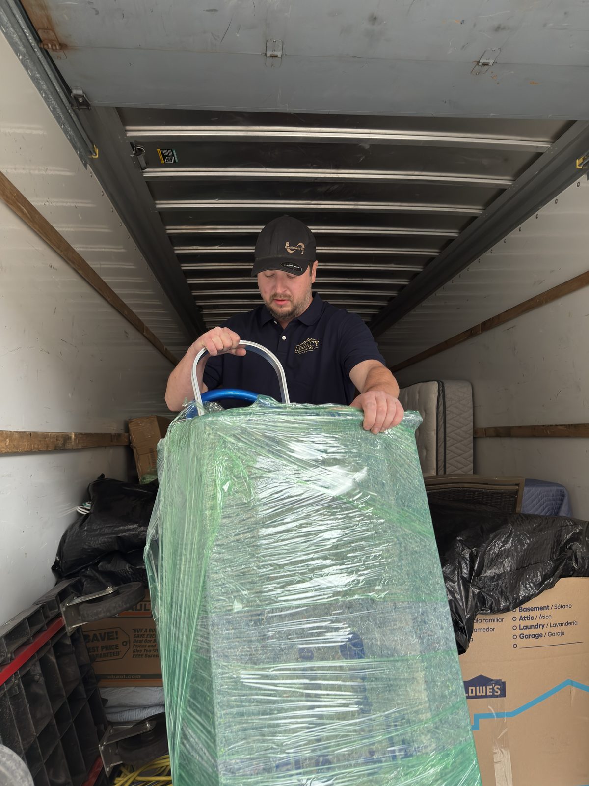 Legacy Moving Co. owner moving wrapped furniture inside a moving truck in Bozeman, Montana